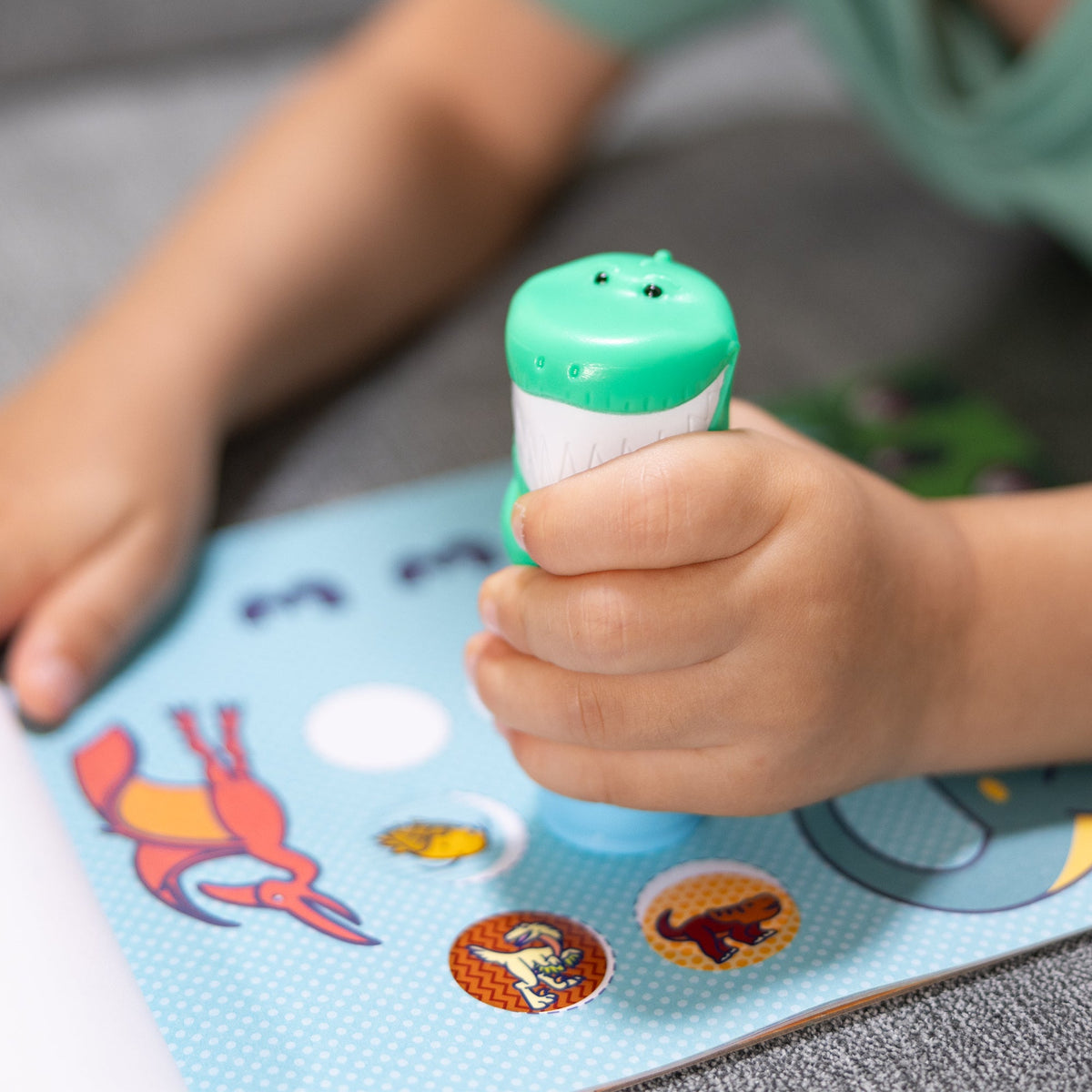 Child stamping dinosaur stickers with the Sticker WOW! stamper